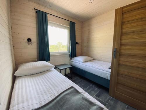 two beds in a room with a window at Single-story holiday cottages, Jaros awiec in Jarosławiec