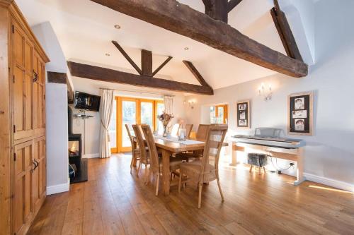 a dining room with a table and a piano at Bank Farm House - Stunning House & Gardens in Shenstone