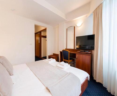 Habitación de hotel con cama y escritorio con TV. en Hotel Pension Matteo en Augsburg