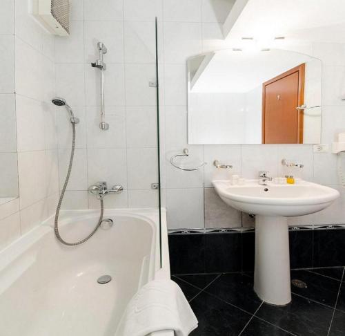 uma casa de banho branca com um lavatório e uma banheira e um lavatório em Hotel Pension Matteo em Augsburg