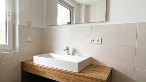 La salle de bains est pourvue d'un lavabo blanc et d'un miroir. dans l'établissement FeWo Hochsiedelblick, Oberstaufen/Wiedemannsdorf, à Oberstaufen