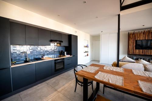 une cuisine avec des armoires noires et une table en bois dans l'établissement Kasa Madura - Duplex au calme tout équipé, à Saint-Étienne