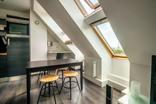 une cuisine avec une table noire et deux tabourets dans l'établissement Rouen, appartement sous les toits, gare + parking, à Rouen