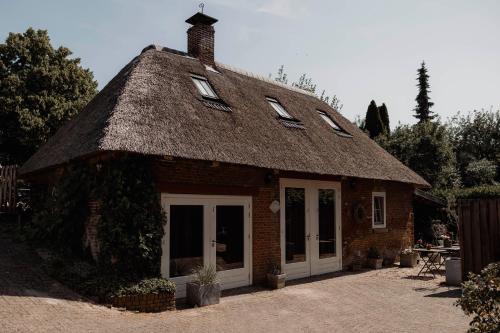 a small brick house with a thatched roof at Het Hart Van Alem in Alem