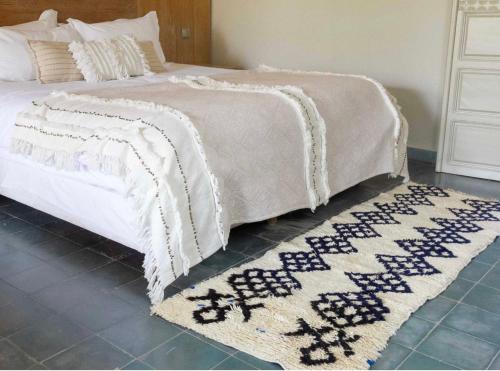 - un lit blanc avec un tapis au sol dans l'établissement Oasis Urbaine - Cosy & Soleil, à Taroudant