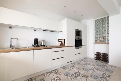 une cuisine avec des armoires blanches et un évier dans l'établissement Angelina - Belle vue mer Le003, à Cagnes-sur-Mer