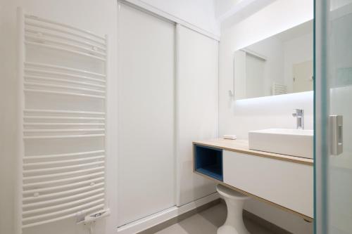 une salle de bain blanche avec un lavabo et un miroir dans l'établissement Angelina - Belle vue mer Le003, à Cagnes-sur-Mer