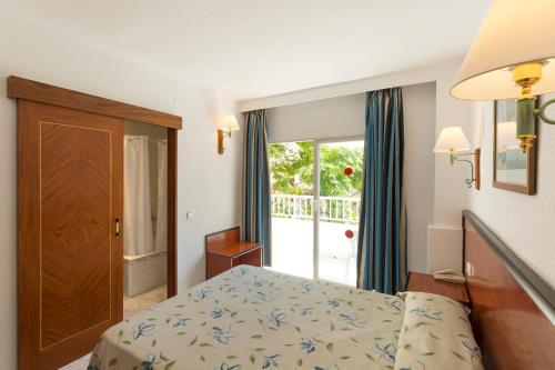 a bedroom with a bed and a sliding glass door at HSM Reina del Mar in El Arenal