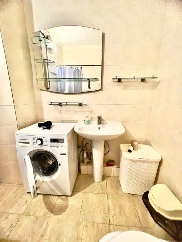 a bathroom with a sink and a washing machine at 224 Чудесный вид на Байтерек с 2 диванами и большой кроватью для 1-5 чел in Astana