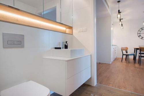 eine Küche mit weißen Schränken und ein Esszimmer in der Unterkunft Apartament Premium PINEA 413 in Pobierowo