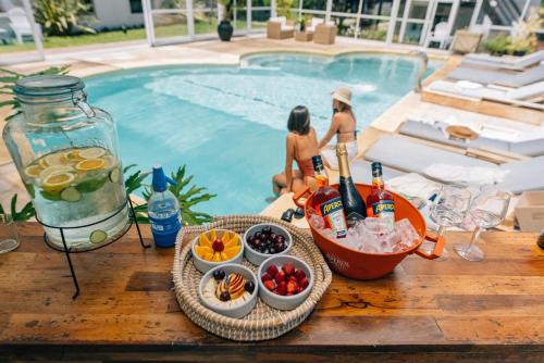uma mesa com comida e bebidas junto a uma piscina em La Galeria - Hotel Boutique Cariló em Carilo