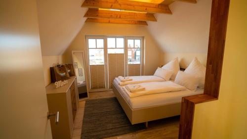 ein kleines Schlafzimmer mit einem Bett und einem Fenster in der Unterkunft Fischerhäuschen am Kurpark in Neuharlingersiel