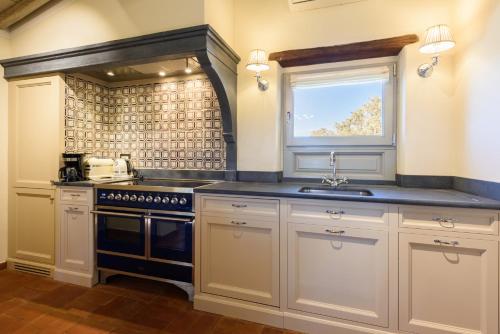 a kitchen with white cabinets and a sink and a window at Villa Conca d'Oro by Mmega in Greve in Chianti
