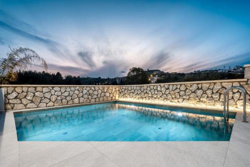 a swimming pool with a stone wall at Eldorado Luxury Villa in Afantou