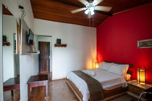 a bedroom with a red wall and a bed at Pousada Namaste in Casa Branca
