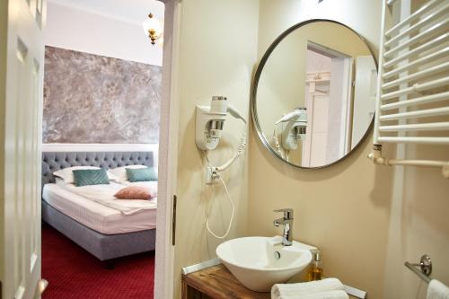 a bathroom with a sink and a mirror and a bed at Charma Residence in Sibiu