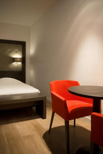 a bedroom with a bed and a table and chair at Parkhotel Kortrijk in Kortrijk