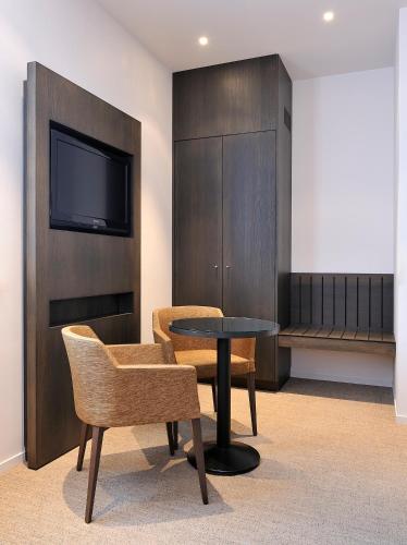 a room with a table and chairs and a tv at Parkhotel Kortrijk in Kortrijk