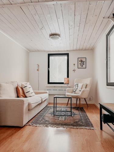 a living room with two white couches and a table at Luxurious red cottage with wood stove near lake in Nye