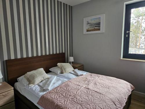 a bedroom with a bed with a striped wall at Dwie Sosny z sauną, Sun & Snow in Ustronie Morskie