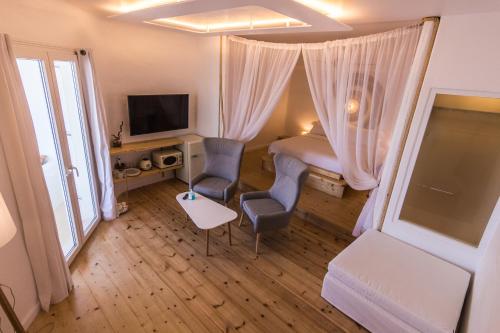 a bedroom with a bed and two chairs and a tv at SALT SUITES MILOS in Pollonia