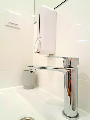 a chrome sink in a white bathroom with at Apartament Nova in Racibórz