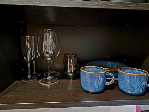 a shelf with three cups and wine glasses on it at Apartament Nova in Racibórz