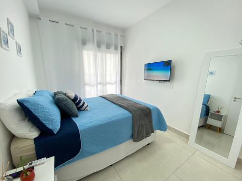 a bedroom with a bed with blue sheets and a window at TULUM Bertioga - belo apartamento com vista para o mar in Bertioga