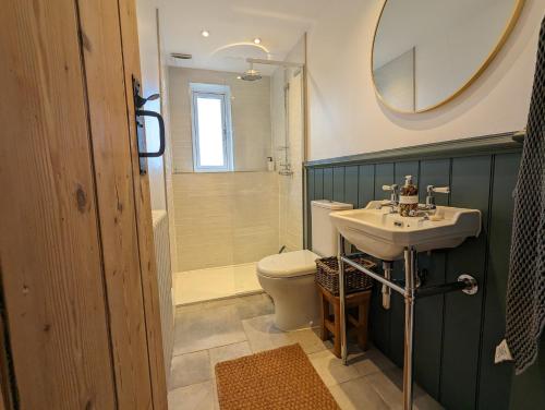 a bathroom with a sink and a toilet and a mirror at Merywen Cottage in Conwy