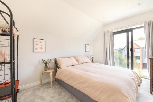 a white bedroom with a bed and a window at Cedar House in Whitstable