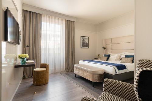 a hotel room with a bed and a chair at Cerretani Hotel Firenze - MGallery Collection in Florence