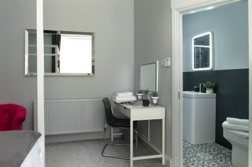 ein Bad mit einem Waschbecken und einem Schreibtisch mit einem Spiegel in der Unterkunft Nythfa in Llanrwst
