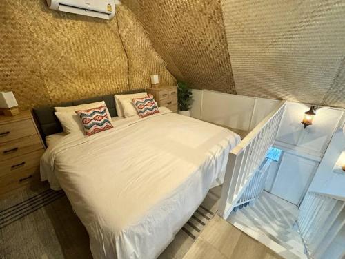 a bedroom with a white bed with two pillows at Beach house steps from the sea in Ban Bang Po