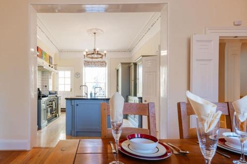 a kitchen and dining room with a wooden table with plates and glasses at Large Central 5 Bed House with Stunning Gardens! in Cheltenham