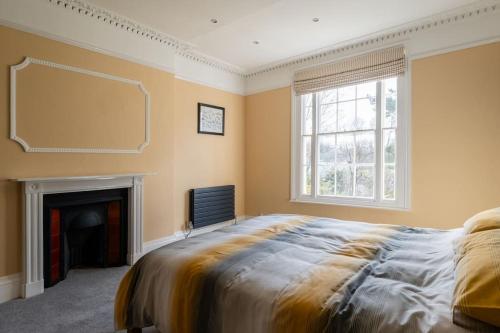 a bedroom with a large bed and a fireplace at Large Central 5 Bed House with Stunning Gardens! in Cheltenham