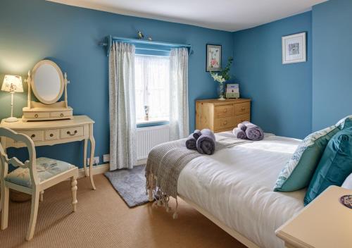 a bedroom with blue walls and a bed with a mirror at Rose Cottage - North Elmham in North Elmham
