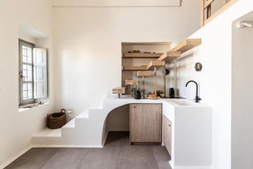 a white kitchen with a sink and stairs at Frescoes Luxury Suites By KB Hospitality in Mesaria