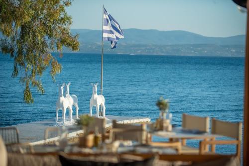 drei weiße Pferde auf einem Tisch neben dem Meer in der Unterkunft Amaronda Resort & Spa Eretria in Eretria