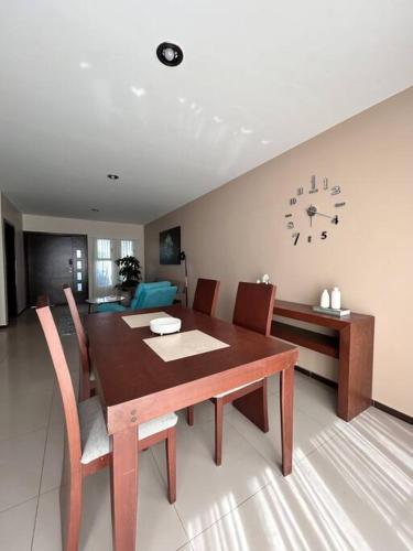 a dining room table with chairs and a clock on the wall at Nueva Galicia residencial, es una propiedad completa al sur de la ciudad que te ofrece modernidad, espacio, tranquilidad, cuenta con 4 recamaras 3 baños completos y 2 cajones de estacionamiento privados in Guadalajara