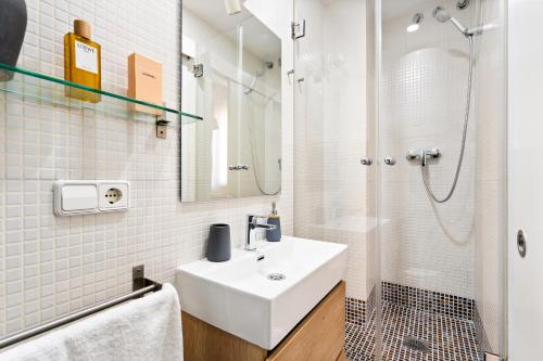 a white bathroom with a sink and a shower at Lodging Apartments Almirall Beach 51 in Barcelona