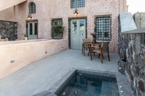 a patio with a table and a swimming pool at Frescoes Luxury Suites By KB Hospitality in Mesaria