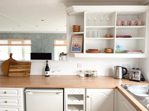 a kitchen with white cabinets and a wooden counter top at Stunning Waterfront Lodge in Christchurch