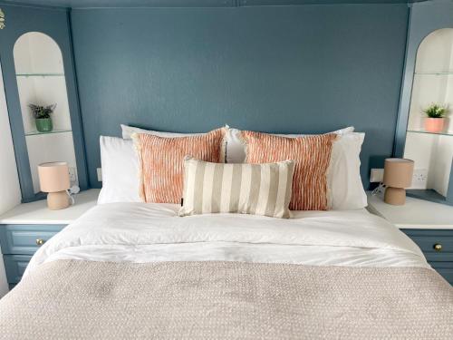 a blue bedroom with a bed with white sheets and pillows at Stunning Waterfront Lodge in Christchurch