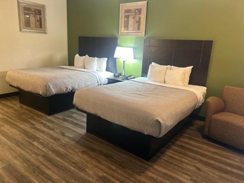um quarto de hotel com duas camas e uma cadeira em Quality Inn em Tullahoma
