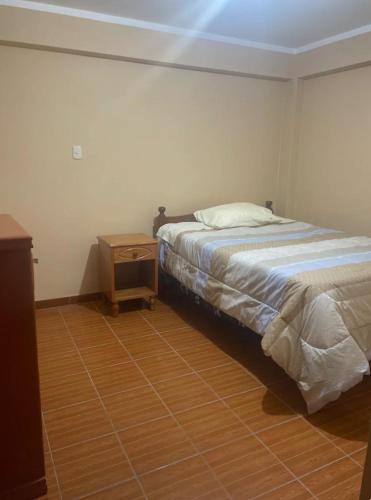 1 dormitorio con 1 cama y mesita de noche al lado en Casa en la ciudad, en Huaraz