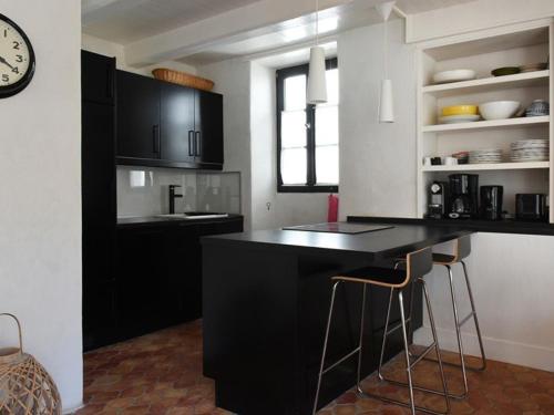 a kitchen with black cabinets and a counter with stools at Maison Les Portes-en-Ré, 4 pièces, 6 personnes - FR-1-434-17 in Les Portes