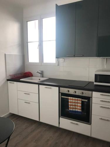 eine Küche mit weißen Schränken und einem Herd mit Backofen in der Unterkunft Appartement confortable à Saint-Jean-de-Luz 45 m² avec cheminée in Saint-Jean-de-Luz