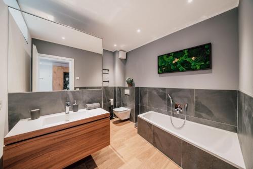 ein Badezimmer mit einer Badewanne, einem Waschbecken und einem WC in der Unterkunft Modern Apartm. Wanderlust with Home Cinema in Echternacherbrück