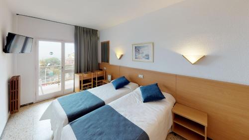 a hotel room with two beds and a window at Hotel Samba in Lloret de Mar