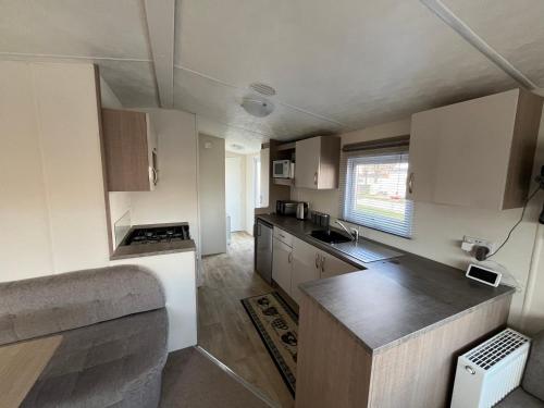 een kleine keuken met witte kasten en een aanrecht bij 28 Trent view in Cottam